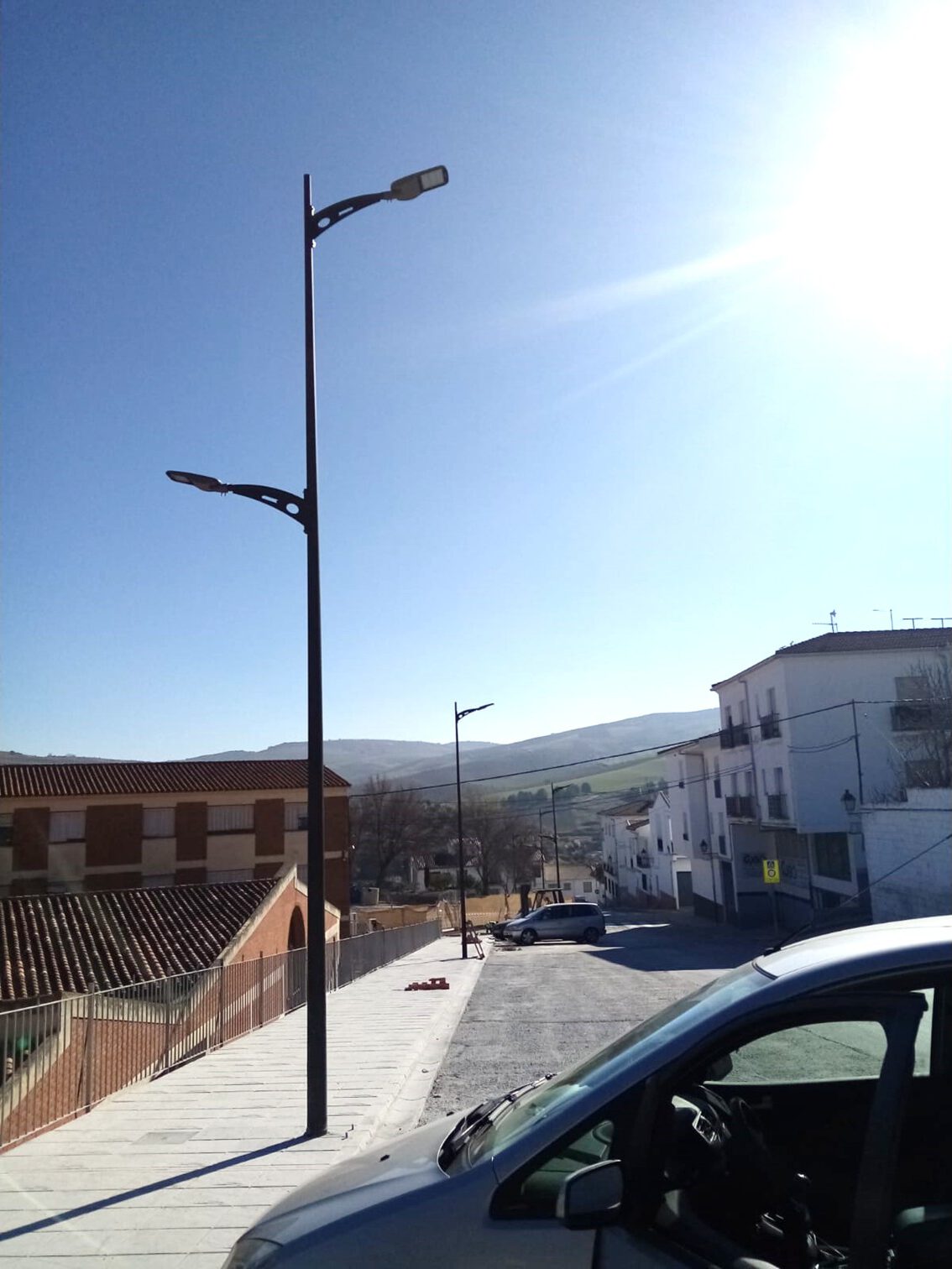 luminaria bora H9 instalada en un entorno urbano junto a un brazo decorativo